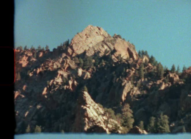 Pine trees growing on the rugged slopes of a mountain at morning caught on vintage film
