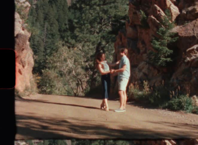 Old film footage of a man and woman dancing in a forest in super 8 film
