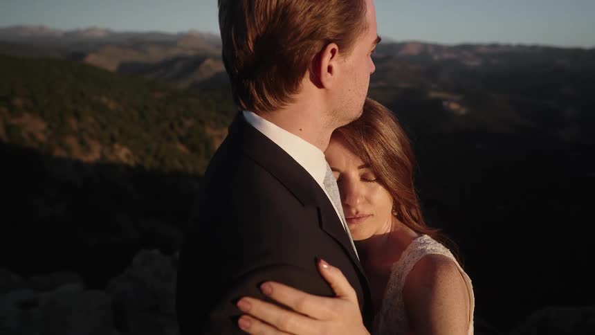 A man and woman hold each other while dressed for a wedding