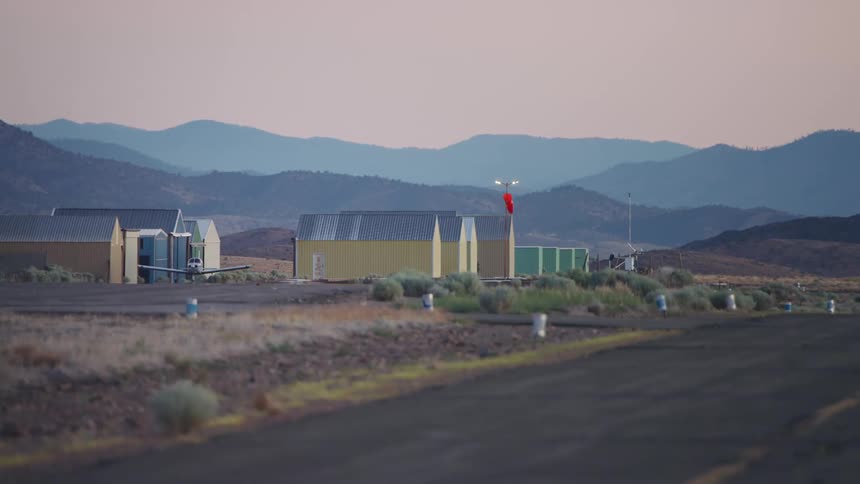 A small single engine airplane taxis near the runway at a small airport early in the morning