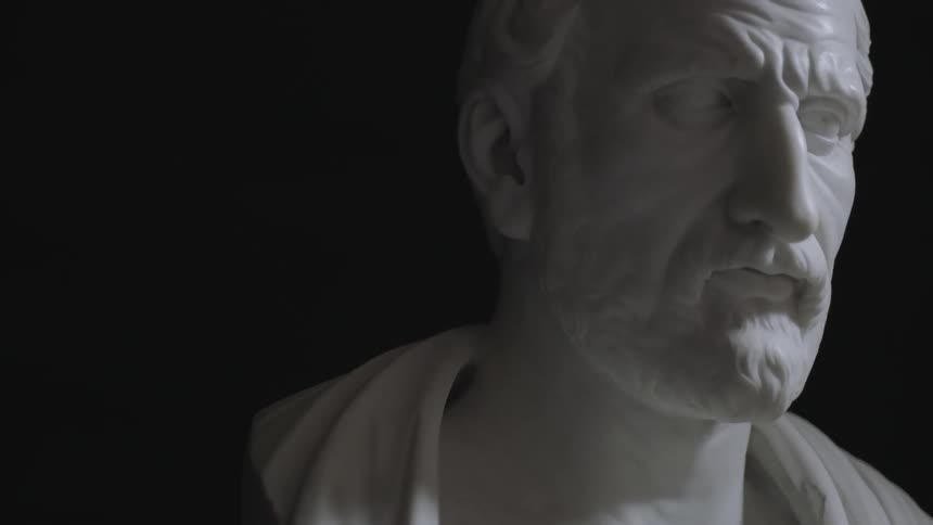 A bearded, white statue in a dark room