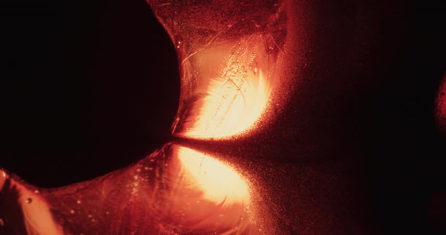 Organic red particles are flowing across a glowing environment to the darkness on the other side