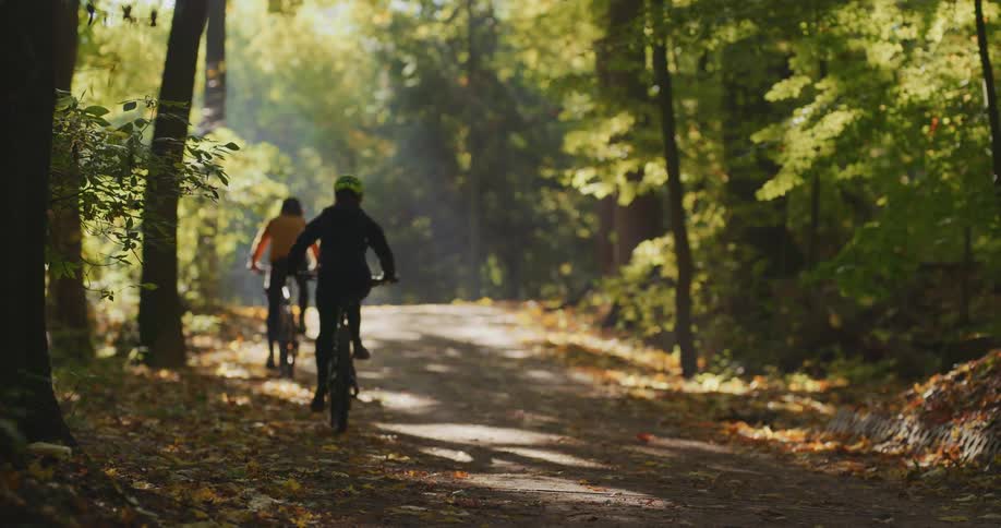 Two people are riding a bike through a wooded area