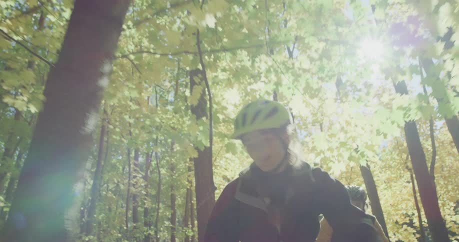 A man and woman chat while riding their bikes through the woods