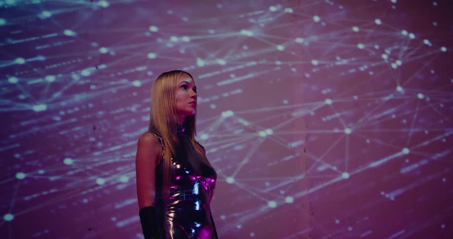 A woman in a sparkly dress stands in front of a wall with projected neon lines