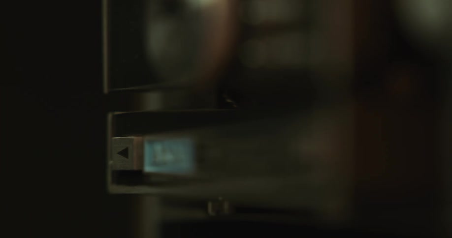 Persons hand presses button on projector in dark room