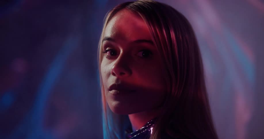 A model poses in front of strobing lights in a dark room