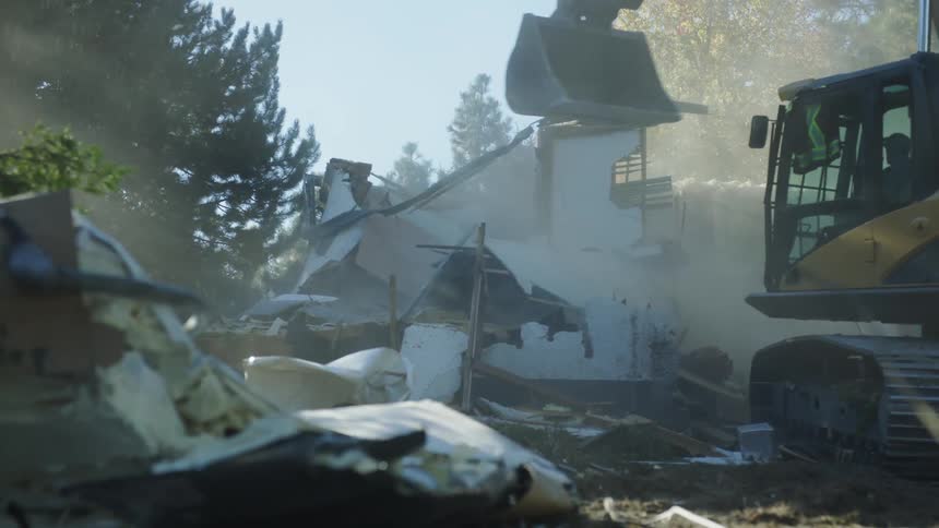 Man drives excavator while demolishing a building