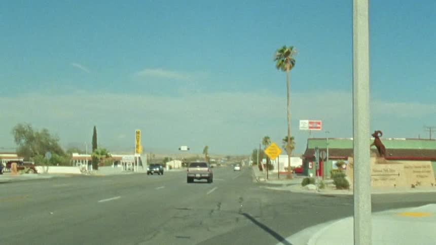 The view is of cars driving down the street in the day time