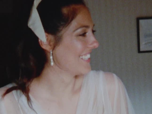 A woman is smiling and wearing a dress indoors