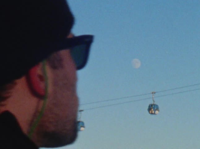 A man watches as ski lifts pass by above him
