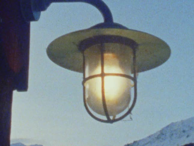 A light post is lit outdoors near the mountains