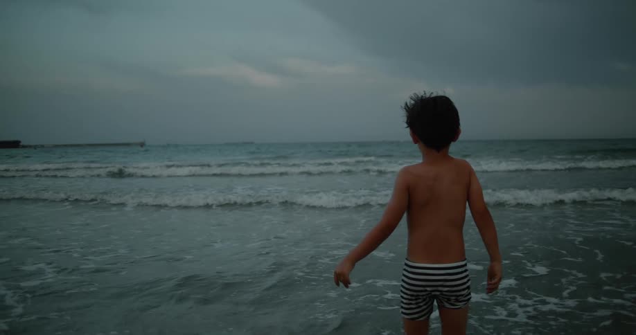 A young child is at the beach in the water in the middle of the day time