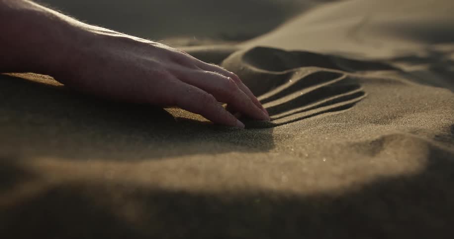 Man pulls his hand through sand leaving finger marks