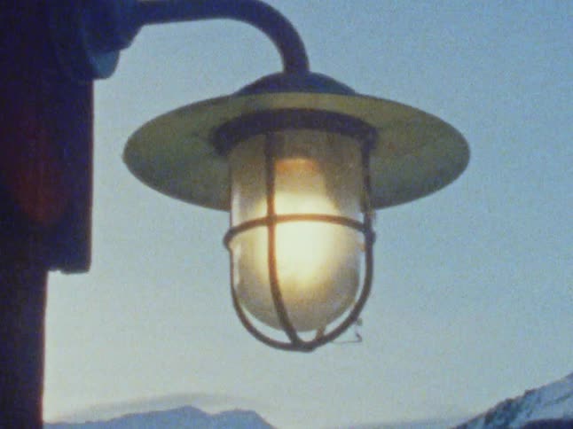Light bulb on a lamp outside a cabin goes off caught on vintage film