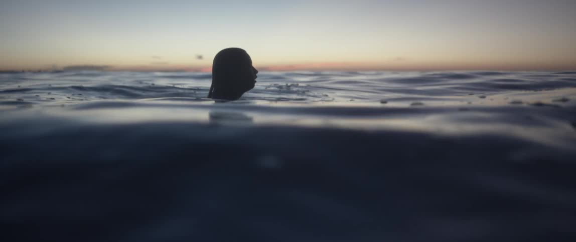 Woman treading water in the ocean at sunset