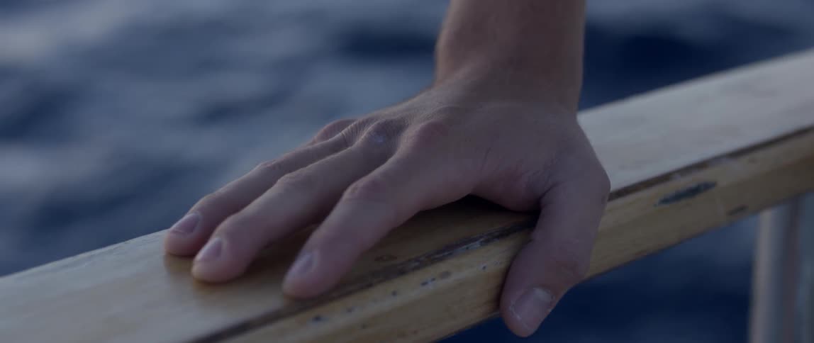 A hand rests on a wooden railing