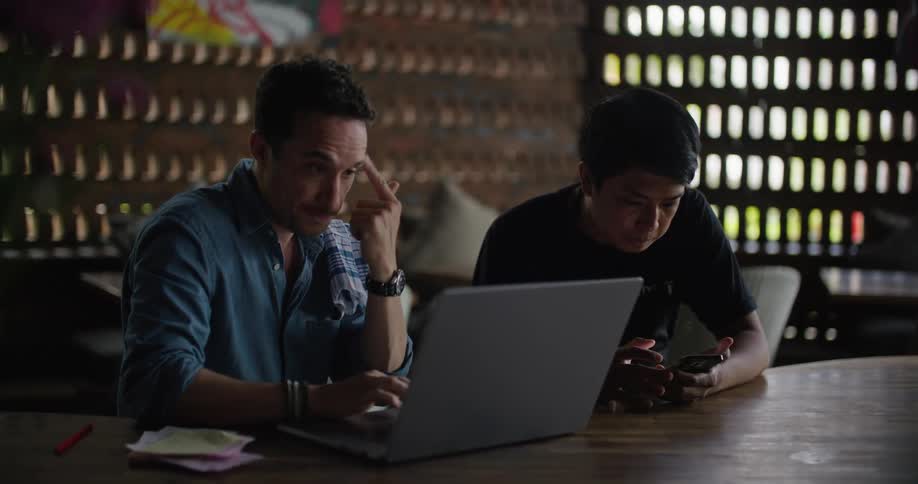 Two men working side by side at a conference table