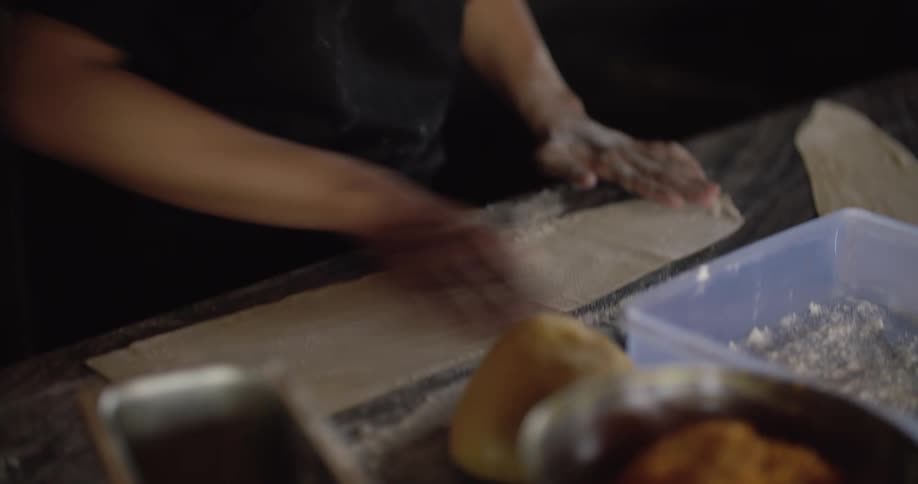 Chef works with thin dough on counter in restaurant