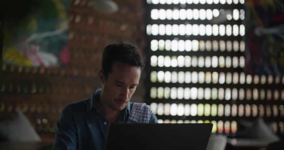 A man typing on a laptop while sitting at a desk