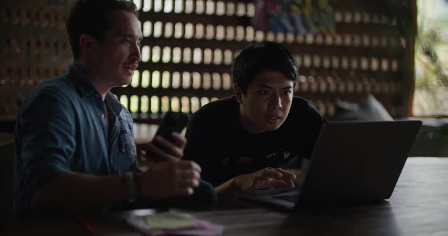 Two coworkers talking while looking at a laptop in office