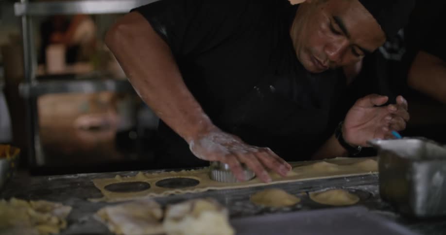Restaurant staff cuts pastries with a cutter on a busy kitchen