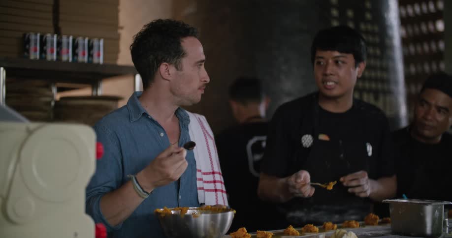 Server tastes the food being prepared by the staff in the kitchen of a restaurant