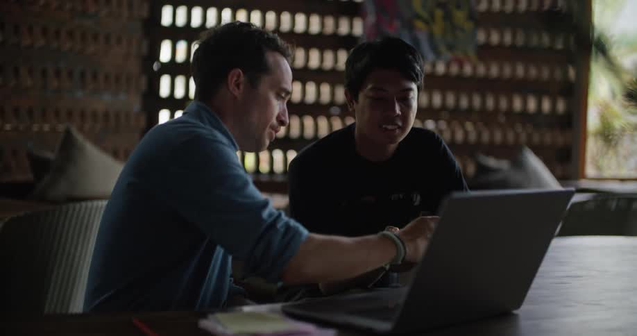Two restaurant workers check paperwork while looking at a smarphone