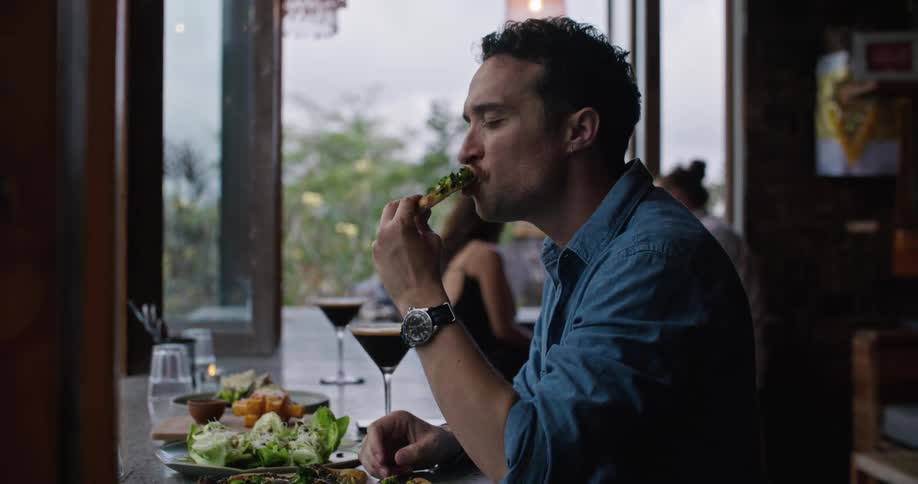 A man eats and drinks alone at a restaurant
