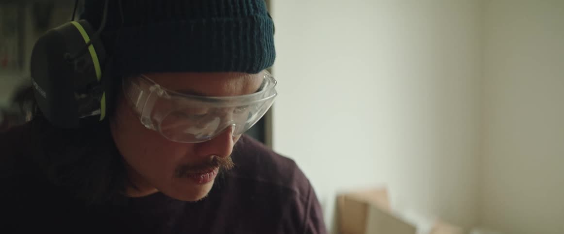 Man wearing goggles and ear protection working in home workshop