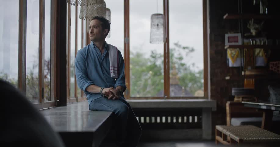 Restaurant owner sitting on a table near a window stands up to start working