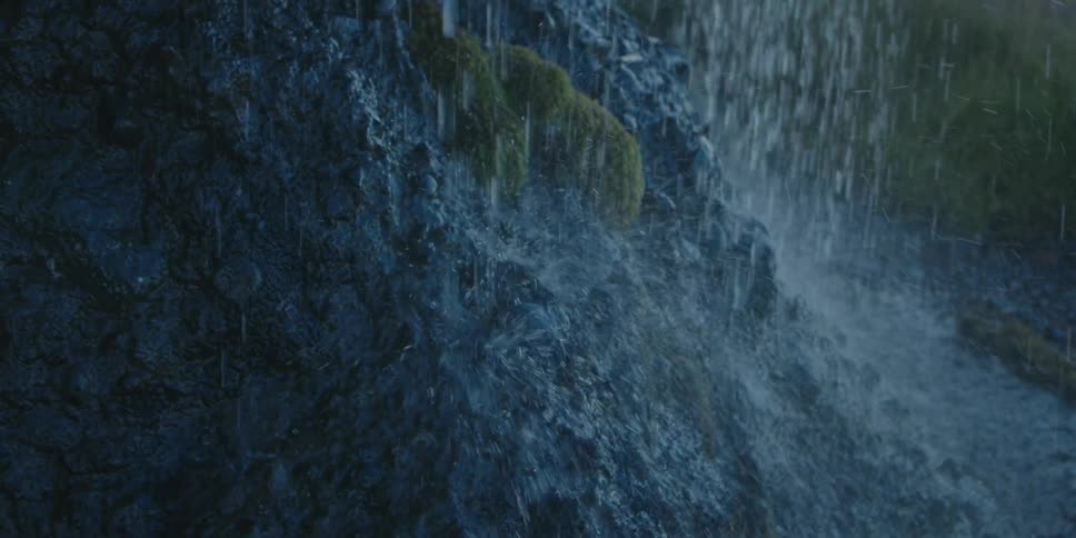 Water from a waterfall trickling down the rocks at the base of a mountain at morning