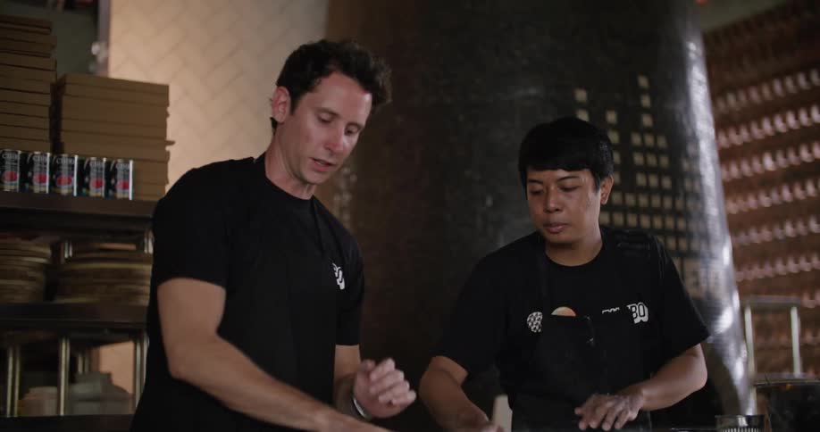 A pair of cooks talk while preparing food together in a restaurant