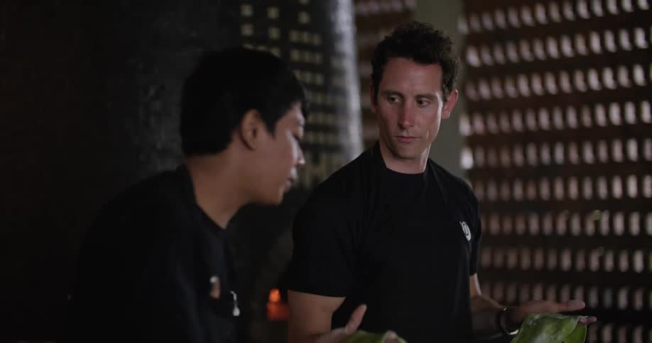 Two male restaurant workers preparing food in the kitchen