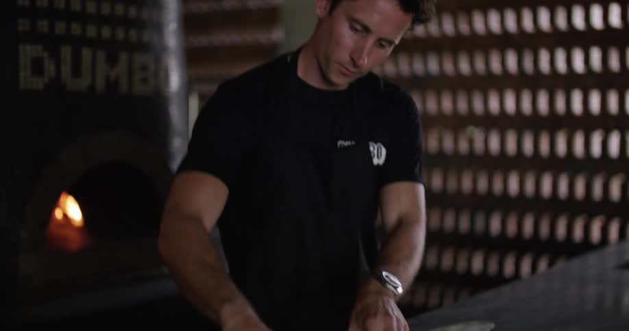 Man kneading dough over the table in the restaurant kitchen