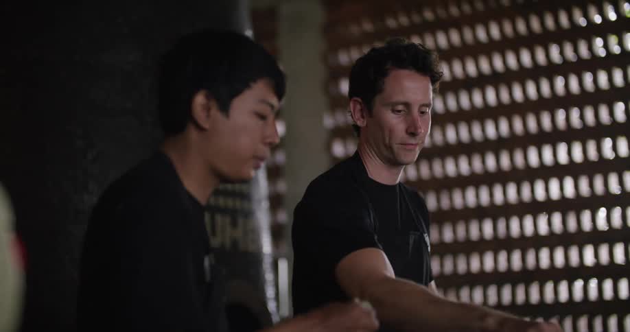 Two people kneading dough over a table on the kitchen