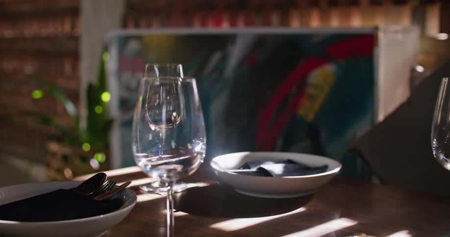 A pair of wine glasses stand empty on a table set with plates