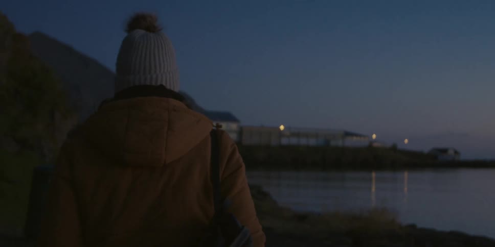 Woman wearing winter clothes walking near a lake in the countryside at evening