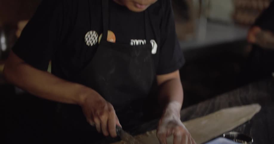 A male restaurant worker cutting food in the kitchen