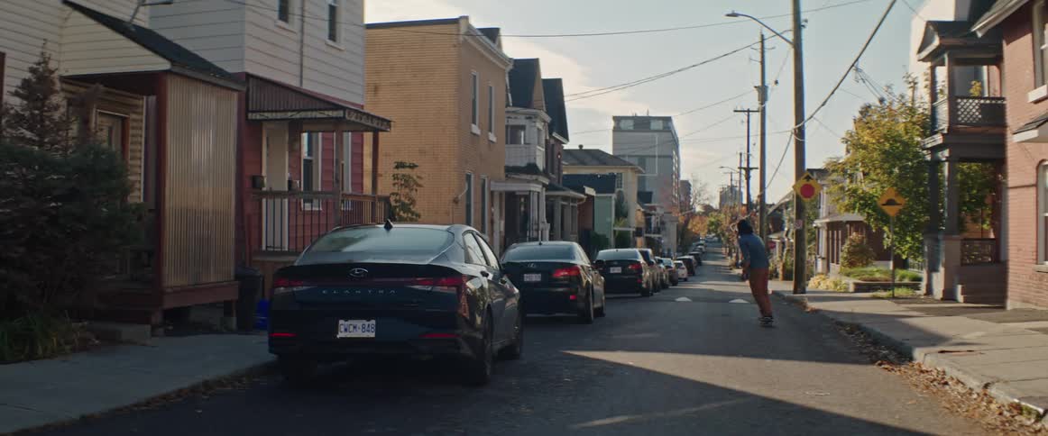 A man rides his skateboard down a neighborhood street