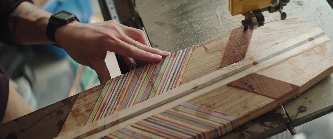 A man is pushing a woodworking project through a saw