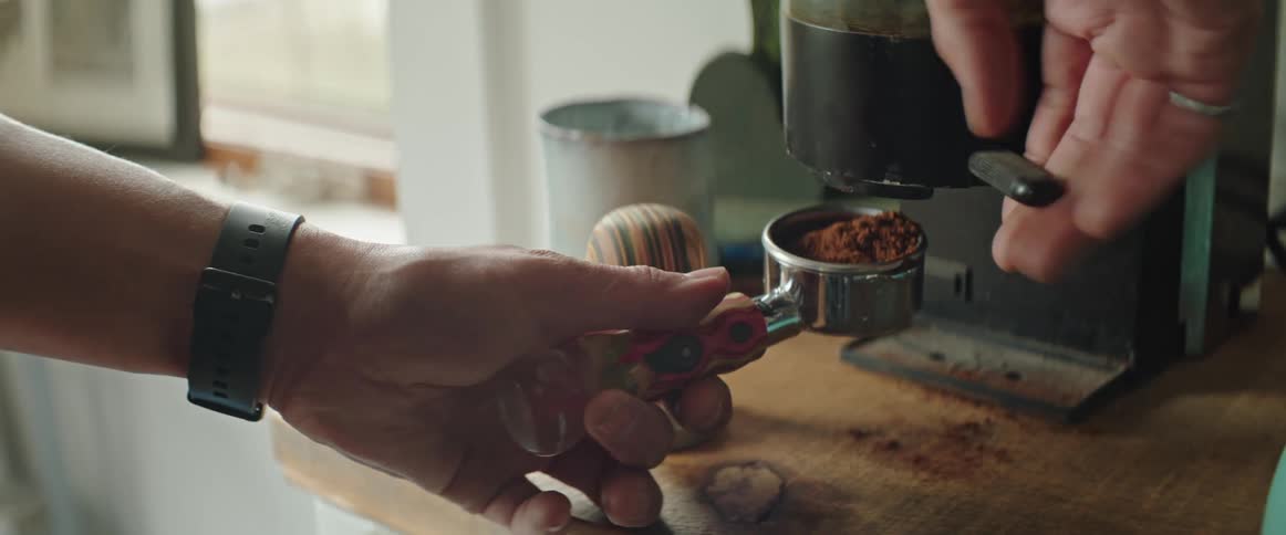 A person preparing coffee grounds for an espresso machine