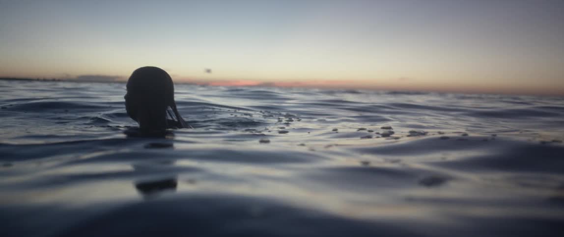 A woman floating in water at sunset