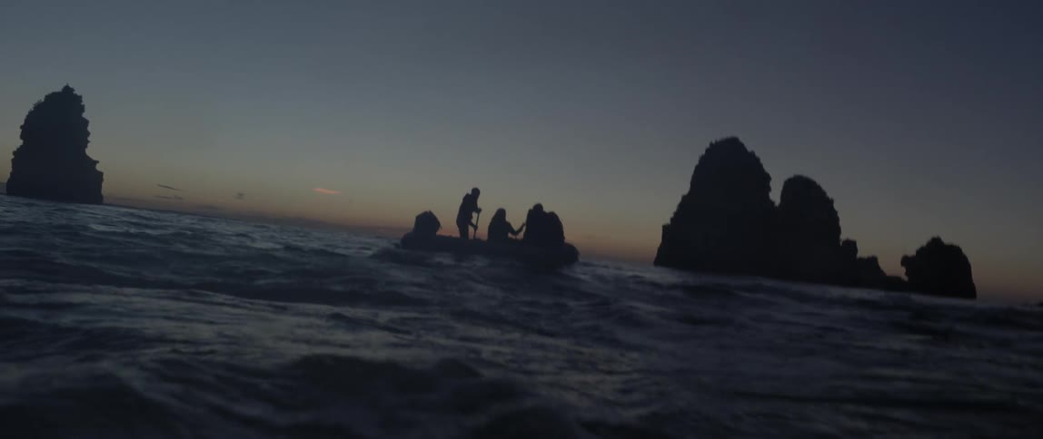 People floating in a raft at sunset
