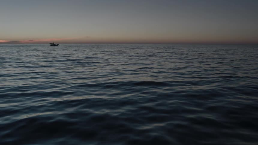 A boat floating on water during sunset