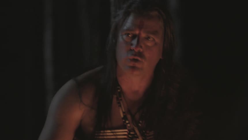 Man standing next to a campfire talking