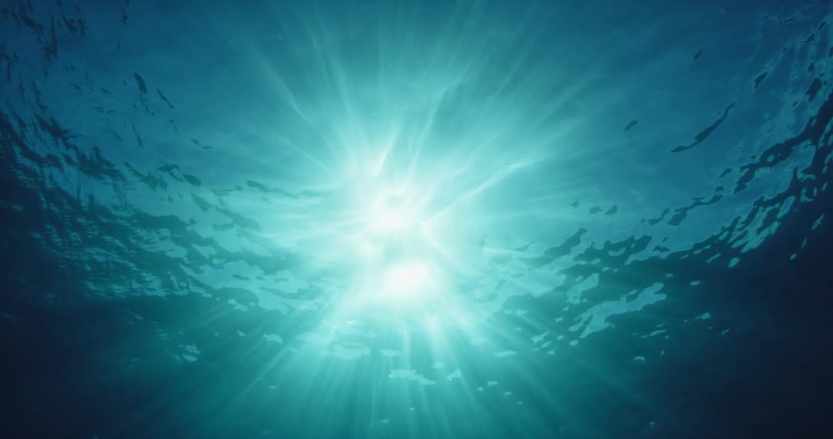 The sun casts bright rays beneath the surface of the ocean