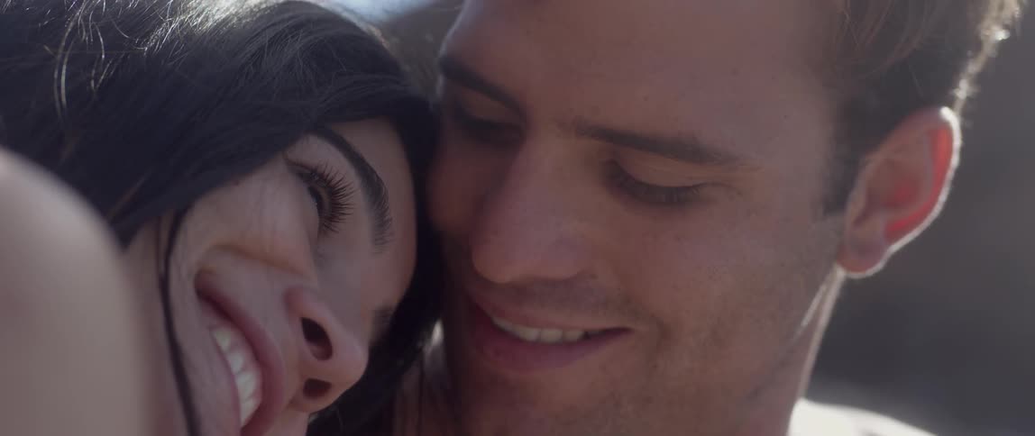 A woman leans her head on a man's shoulder talking