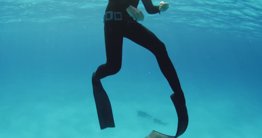 A diver floating up and breaching the surface in the ocean
