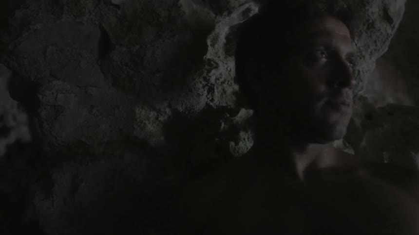 A man standing next to a cave wall